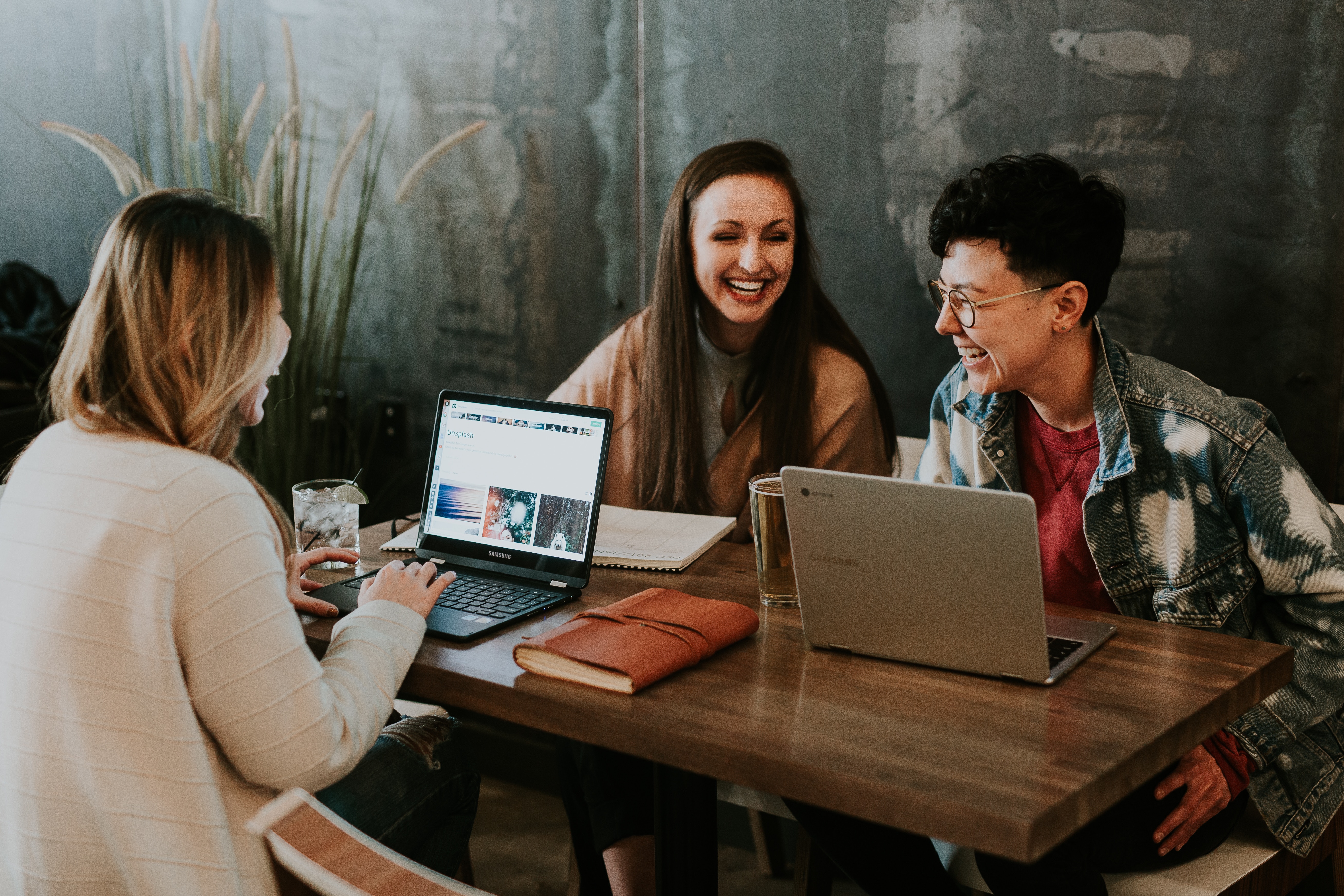 Photograph of three women sitting around a table with their laptops.