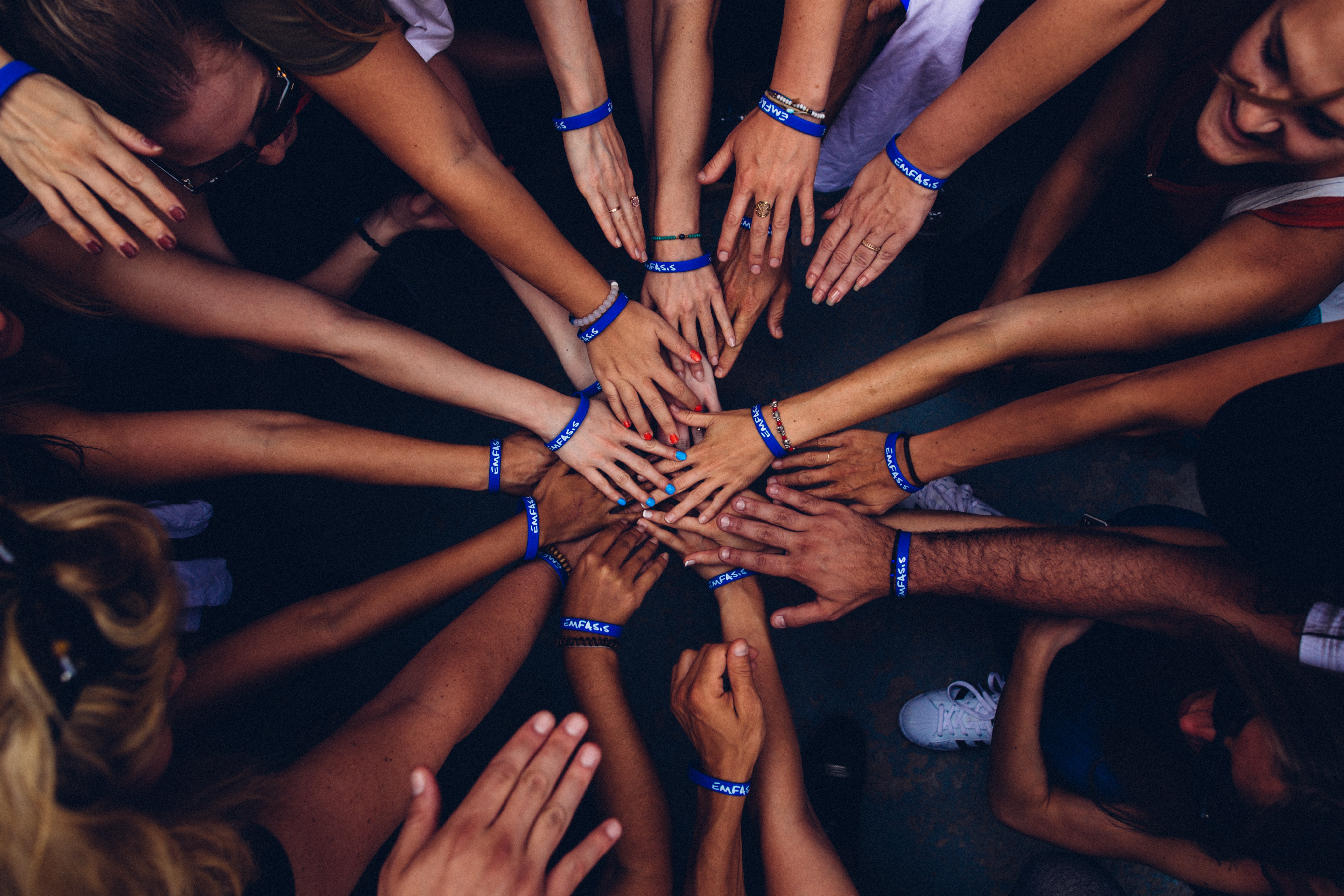 Aerial photograph of several people in a huddle, placing their hands together in the center.