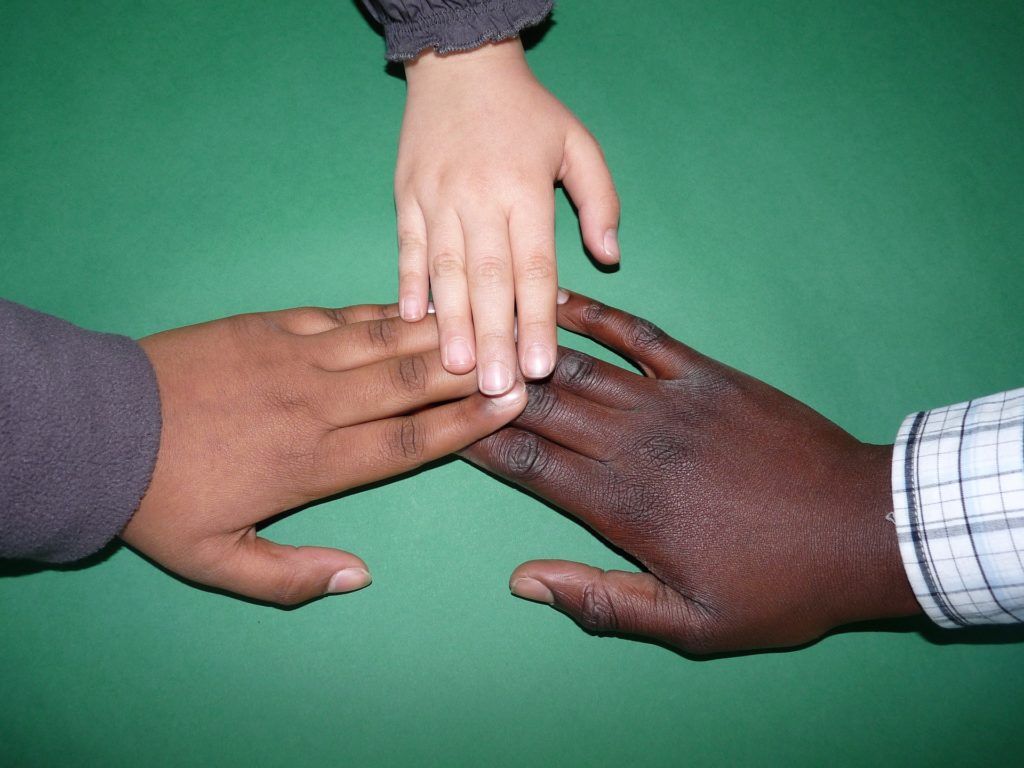 Photograph of three individuals putting their hands together in a symbol of agreement