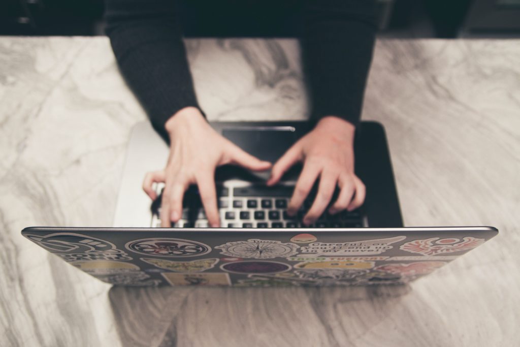 Photograph of a woman typing on a laptop