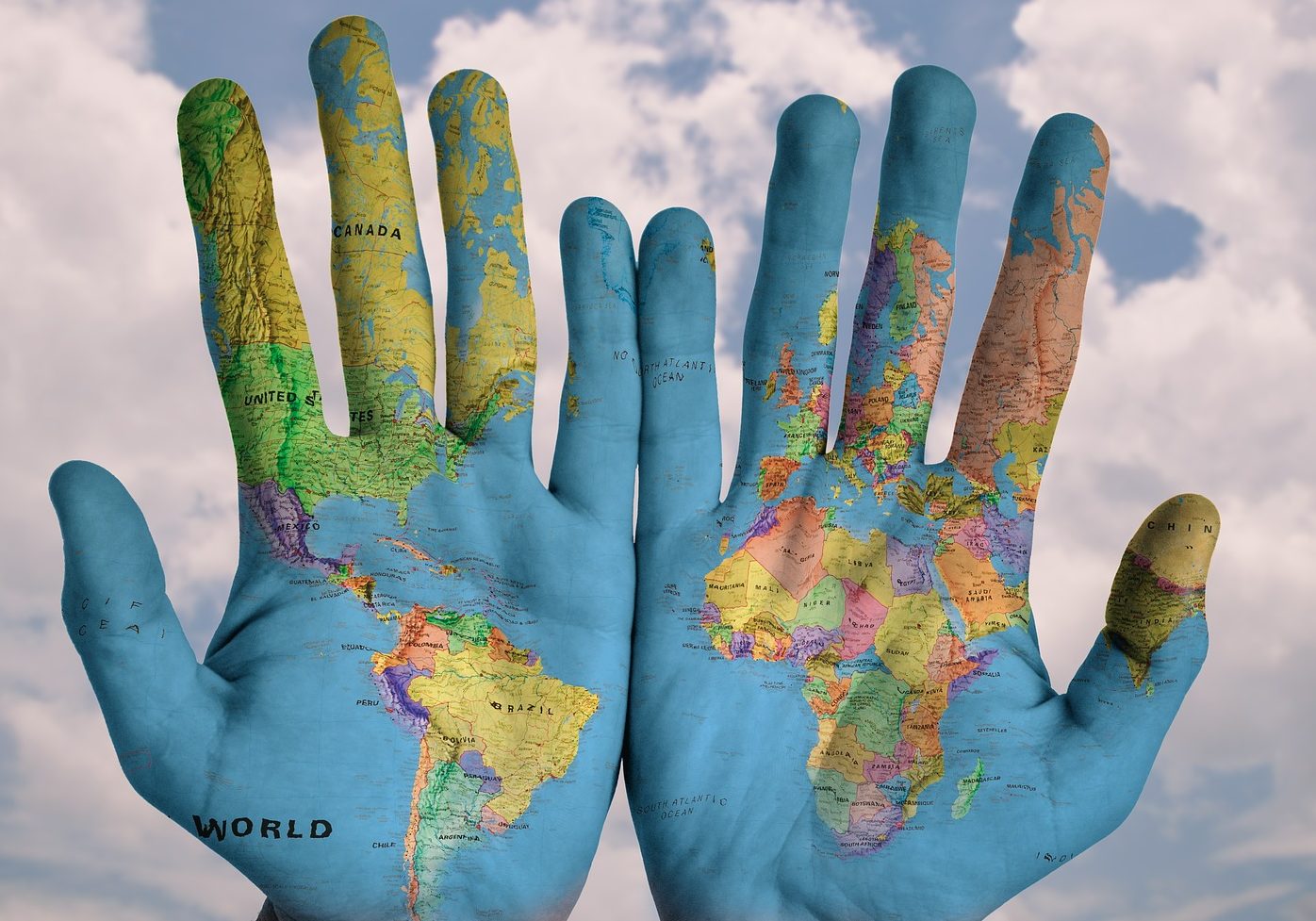 Photograph of someone holding their hands next to one another. A map of the world is superimposed on the hands.