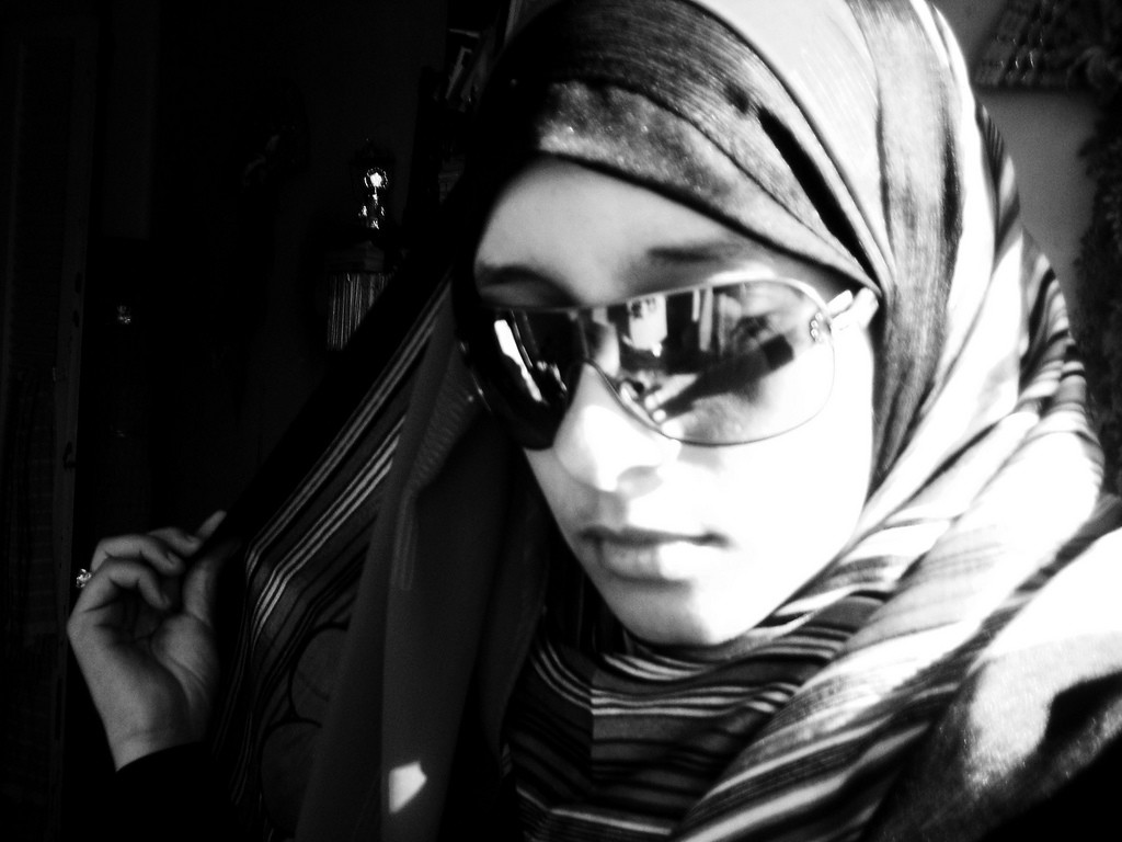 Close-up of a young woman wearing hijab and sunglasses.