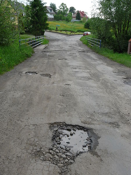 A one-land country road riddled with potholes.