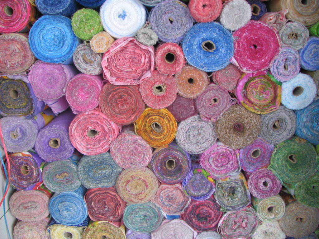 A stack of colorful rolled-up carpets.