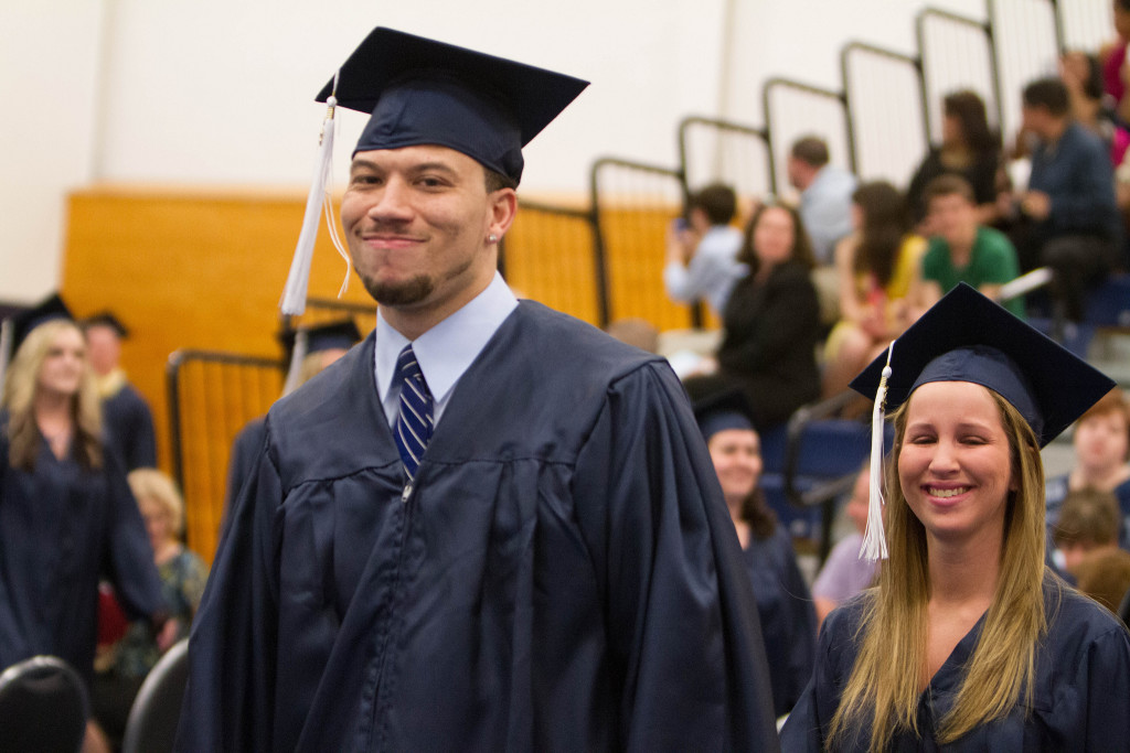 Photo of two students wearing caps and gowns, at graduation.