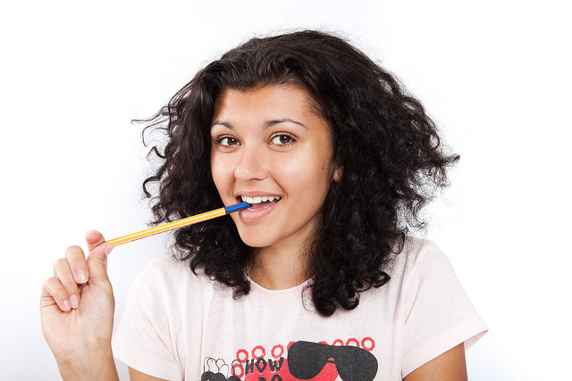 Smiling picture of a college student with a pen in her mouth.