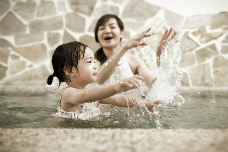 Mother splashing with daughter in a fountain.