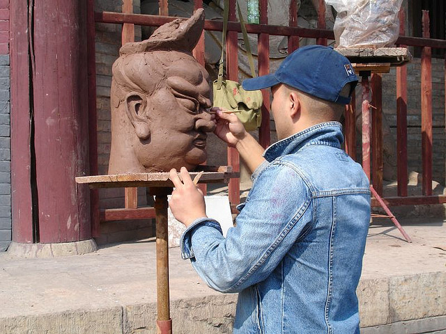 Man working on a sculpture of a face.